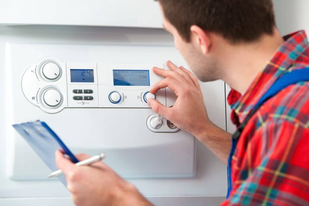 Installateur bedient het paneel van een cv-ketel met een klembord in de hand